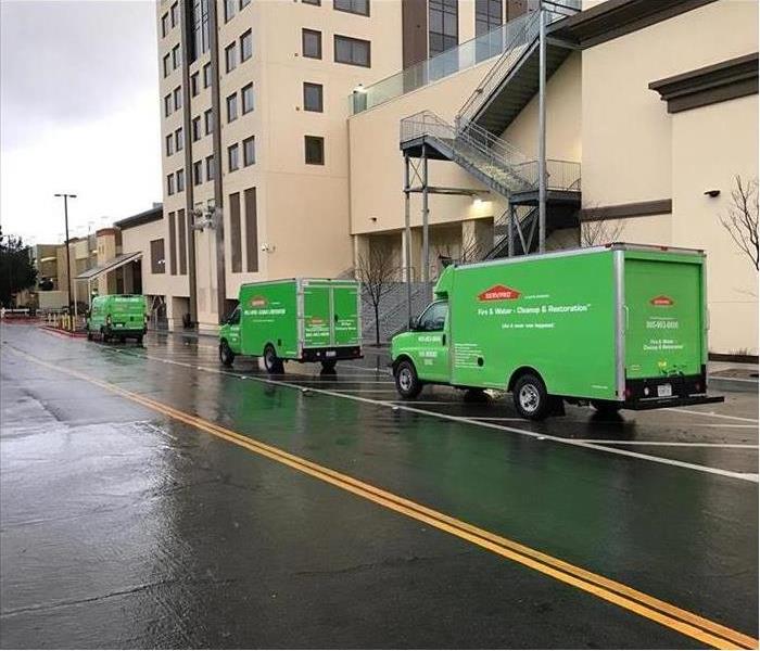 Three green box truck driving down the street