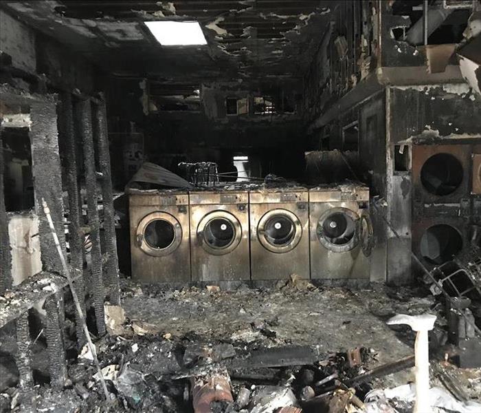 Inside of a laundromat after a large fire with lots of soot, ashes, and debris